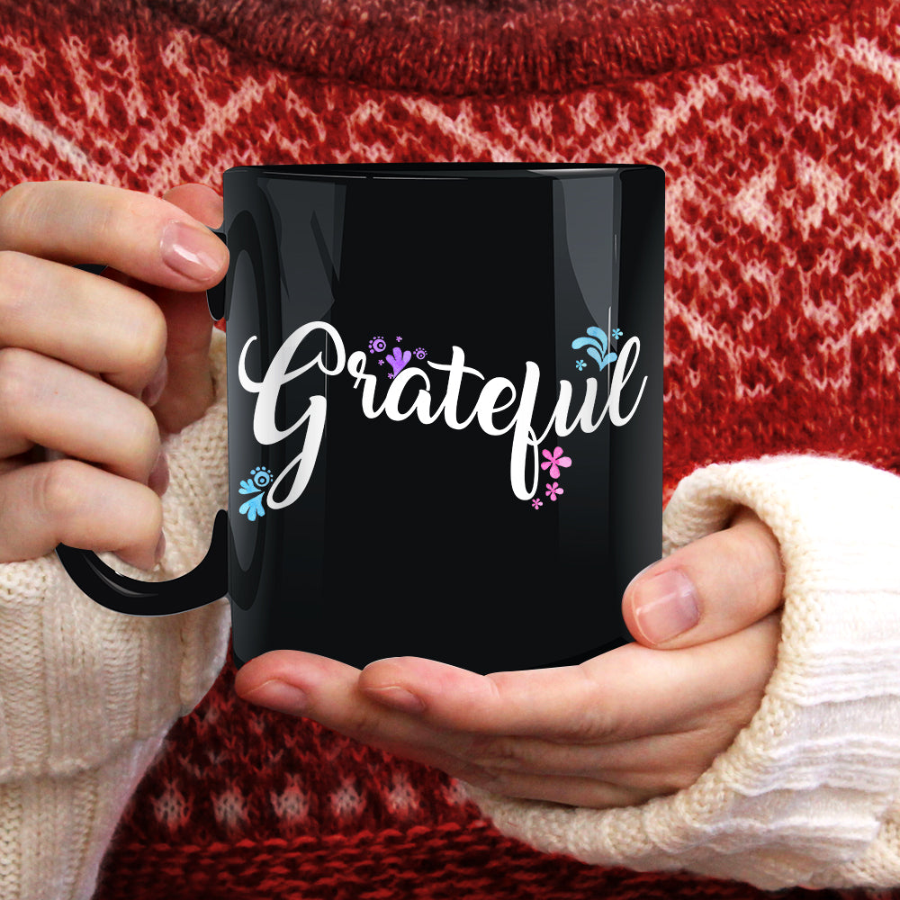 Eleven ounce black coffee mug with the word Grateful written on it with blue purple and pink flowers